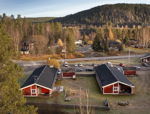 Avstampets behandlingshem i Älvsbyn sett från ovan – två röda hus med skog och berg i bakgrunden